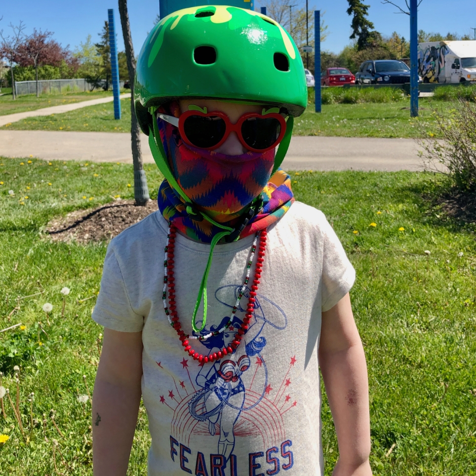 Beatrix in a bike helmet, mask, necklaces, and tshirt that reads, "Fearless"